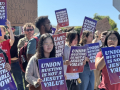 Students and faculty members rally holding signs that say "Union Busting Is Not a Jesuit Value" and "LMU: Back to the Table Now."